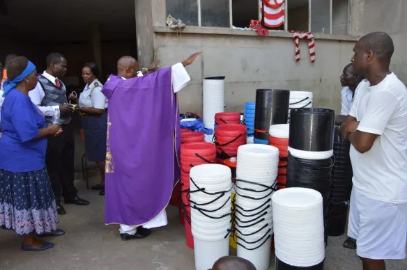 Fr. Kunaka blesses the buckets and slippers donated to Chikurubi Prisoners.JPG