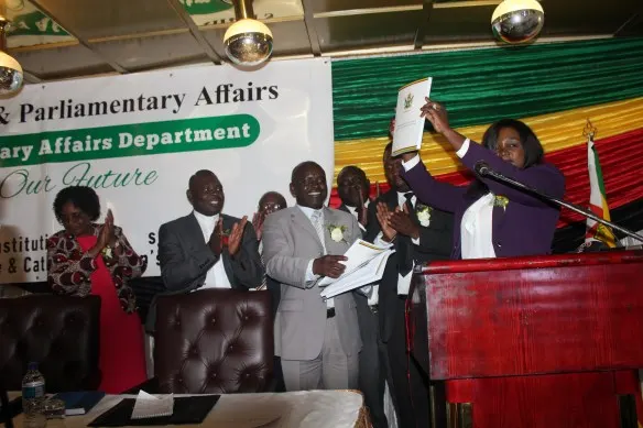 Mrs V. Mabiza shows a copy of the translated version of the constitution while Bishop Nyandoro (clapping) looks on..JPG