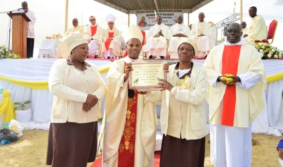 Archbishop Alex Thomas presents a plaque to honour Mrs. Anna Mugadza for her stelling work in the Archdiocese as a catechist for 45 years.